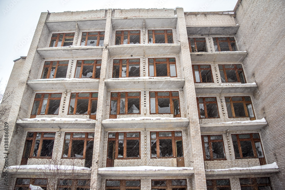 Winter, blizzard, snow, old ruined five-storey building with broken windows 