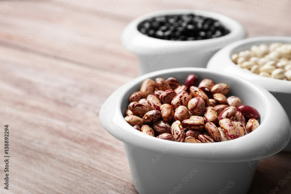 Assortment of haricot beans in bowls on wooden table, closeup Assortment of haricot beans in bowls on wooden table, closeup