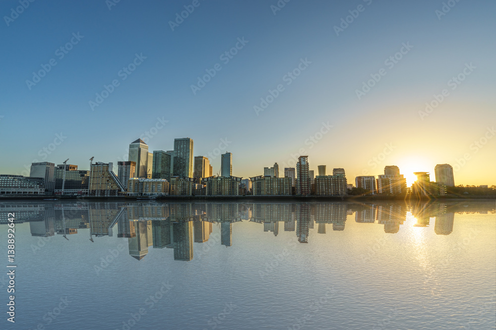 Panorama of Canary Wharf business district with water reflection at sunset