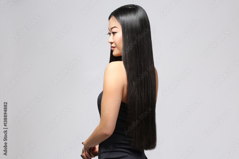 Naklejka premium Beautiful Asian woman with long straight hair on light background