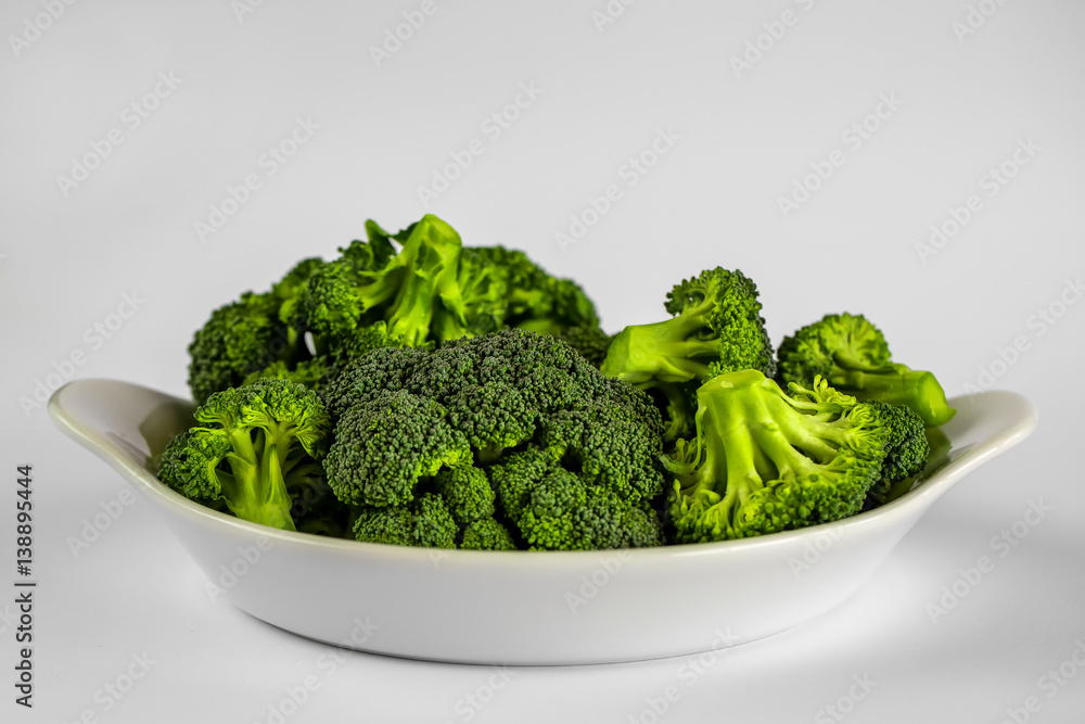 White dish with pieces of broccoli on white background White dish with pieces of broccoli on white background