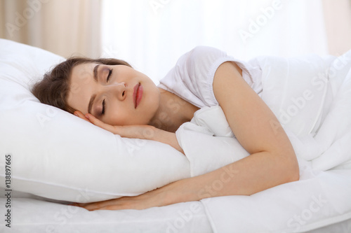 Beautiful young woman sleeping while lying in bed comfortably and blissfully. Early morning, you wake up for work or the day off concept