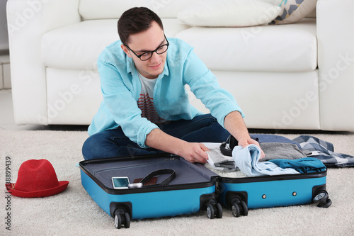 Handsome young man packing ...