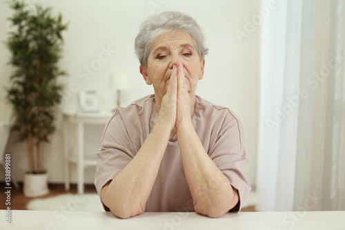Praying elderly woman at home