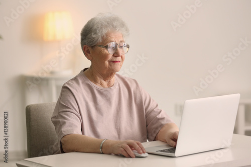 Elderly woman working on la...