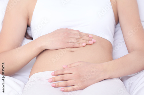 Wallpaper Mural Beautiful pregnant woman touching her belly lying on bed, closeup Torontodigital.ca
