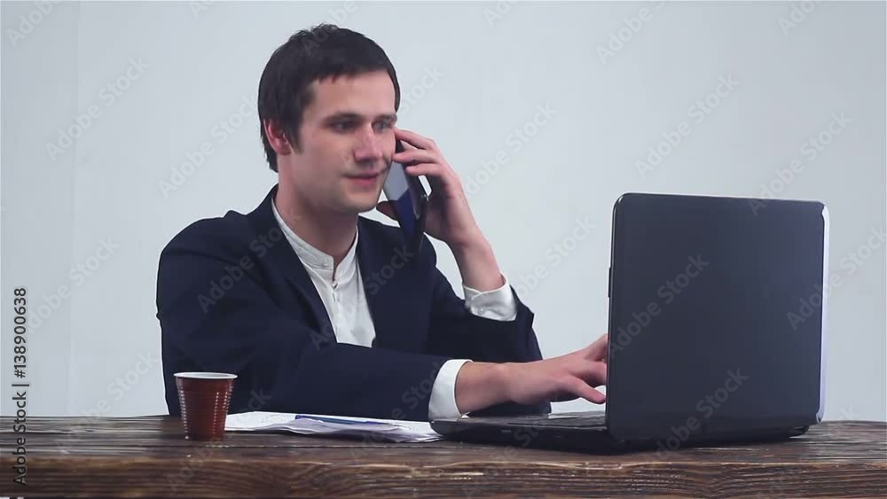 Young businessman talking on the phone and working on a laptop. Young businessman talking on the phone and working on a laptop.