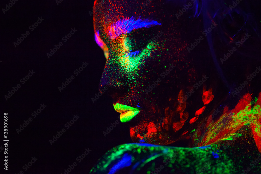 Beautiful extraterrestrial model woman with blue heair and green lips in neon light. It is portrait of beautiful model with fluorescent make-up, Art design of female posing in UV with colorful make up