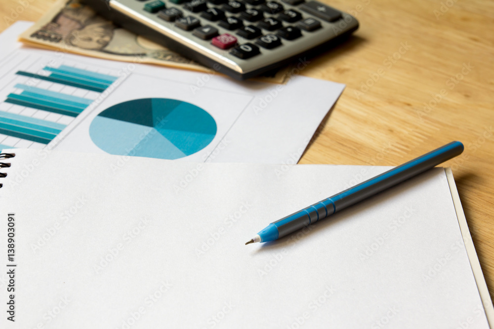 Note book with calculator, financial graph, pen, japanese yen on wooden table background Note book with calculator, financial graph, pen, japanese yen on wooden table background