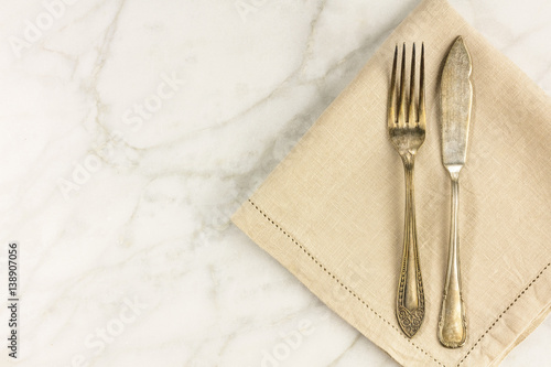 Vintage fork and knife on white marble table with copyspace