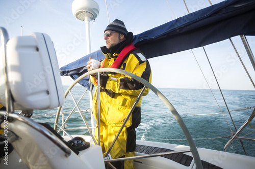 Man Holding Coffee Cup While Standing At Helm Of Yacht