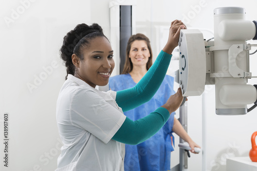 Tableau sur toile Radiologist Adjusting X-ray Machine Over Woman In Hospital
