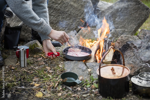 Man Cooking Food Over Bonfire At Campsite