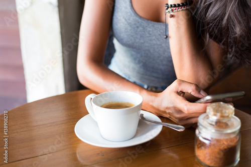 Young adult girl enjoying coffee and breakfast at a cafe 
