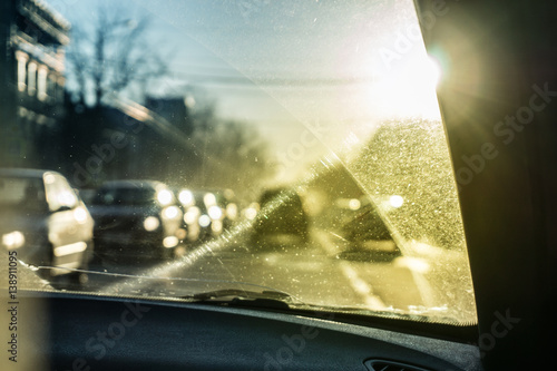 Car glass with unclean texture. Blurred road on background. Morning sunlight.