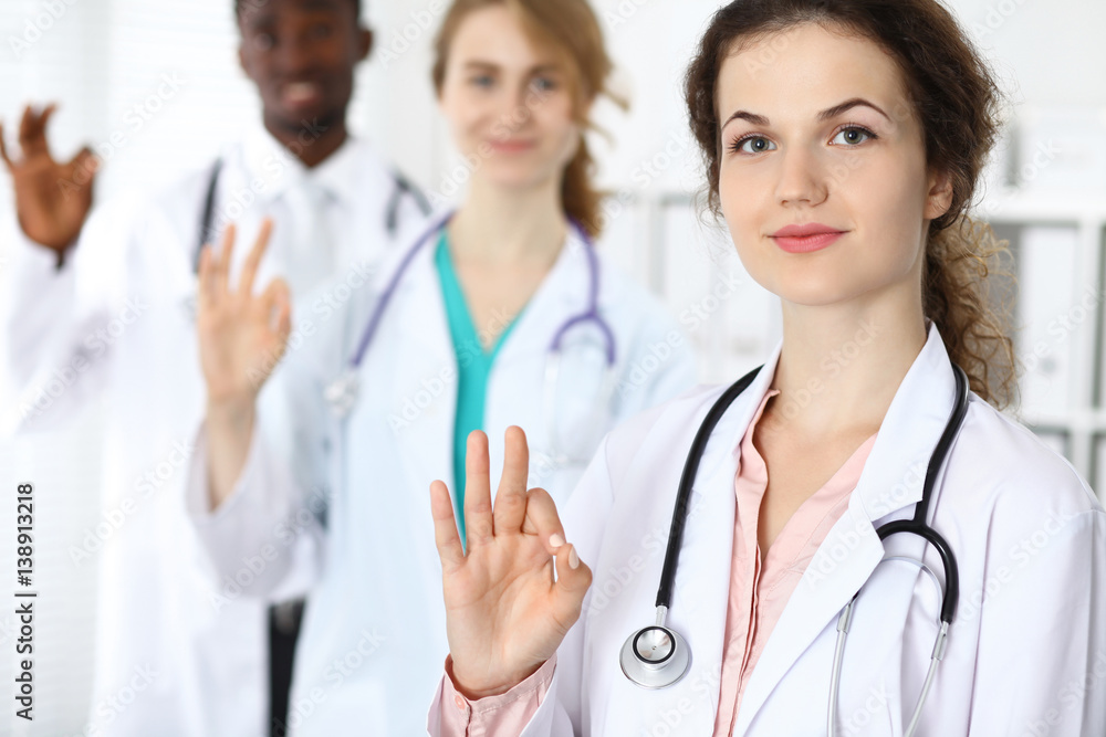 Medical team of confident doctors showing Ok sign and ready to help. Medicine and health care, insurance concept Medical team of confident doctors showing Ok sign and ready to help. Medicine and health care, insurance concept