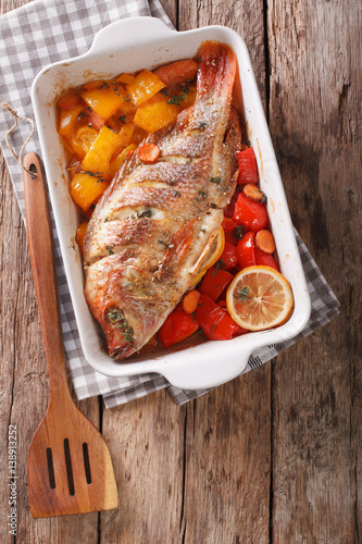 Baked tilapia with sweet pepper, carrot, lemon and thyme close up. vertical top view photo