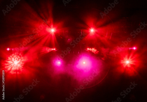 The red light from the spotlights through the smoke at the theater during the performance. Lighting equipment.