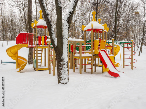 Snowy colorful playground in a park in winter.