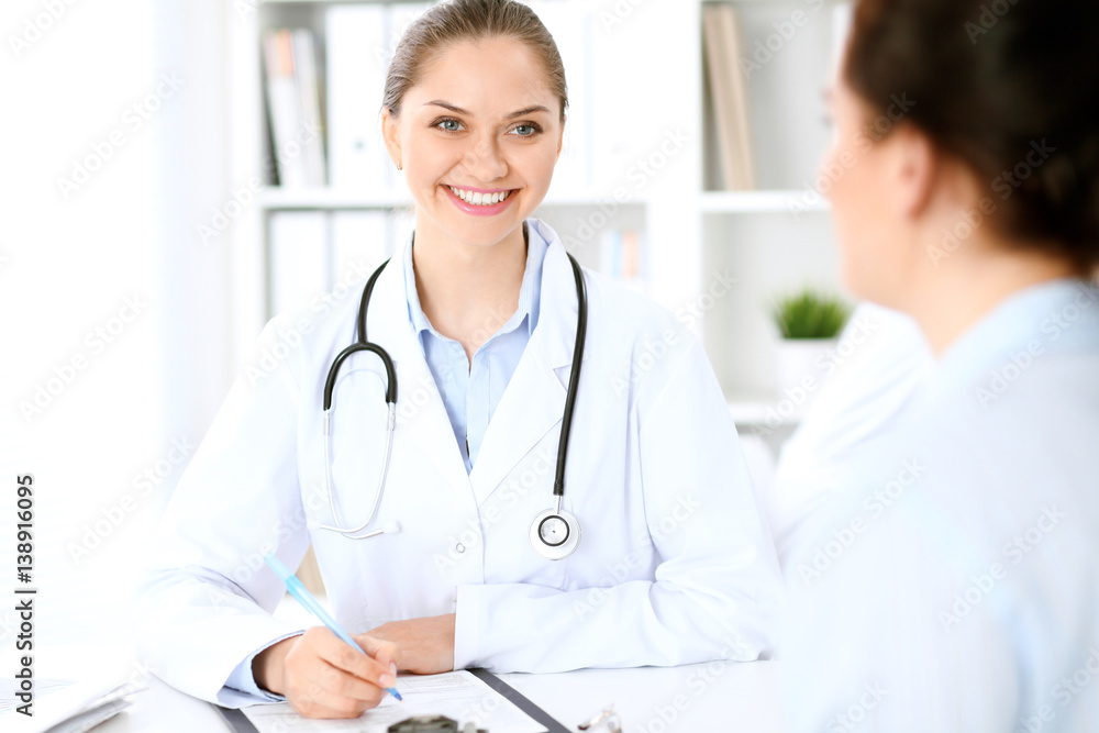 Friendly smiling doctor and patient sitting at the table. Very good news and high level medical service concept. Friendly smiling doctor and patient sitting at the table. Very good news and high level medical service concept.