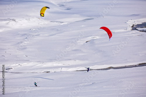 people doing kitesurfing on a frozen mountain lake