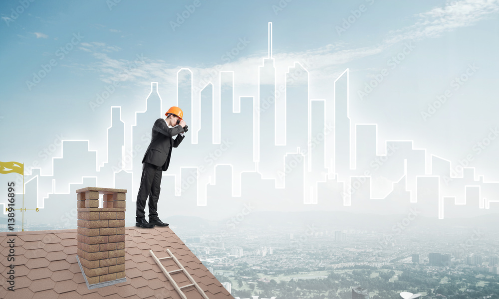 Engineer man standing on roof and looking in binoculars. Mixed media Engineer man standing on roof and looking in binoculars. Mixed media