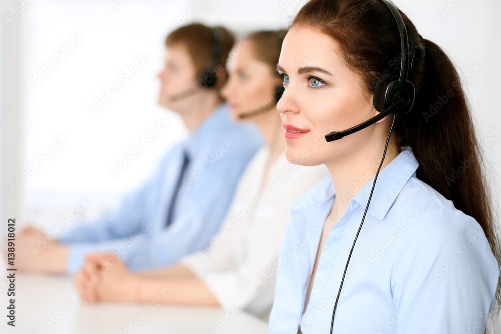 Call center operators. Focus at brunette business woman in headset Call center operators. Focus at brunette business woman in headset