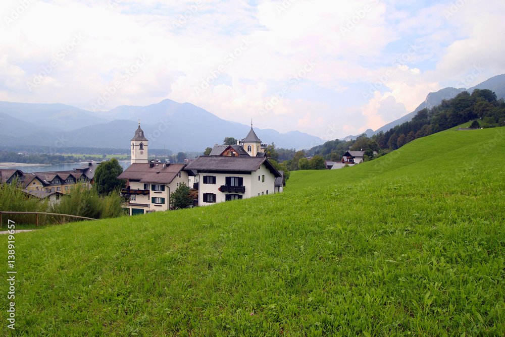 Travel to Sankt-Wolfgang, Austria. The green meadow with the houses in the mountains.