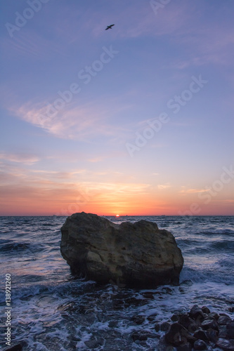 Sunrise on the sea shore with clouds in the sky. Big stone photo