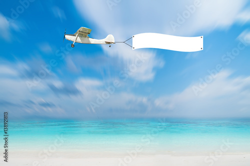 Antique Airplane with advertise board banner fly on blue sea view with blue sky, Thailand.