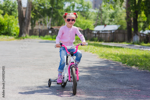Fototapeta Naklejka Na Ścianę i Meble -  Little girl on a bicycle in summer park outdoors