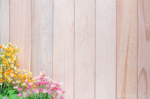 Artificial flowers on wooden plank with copy space.