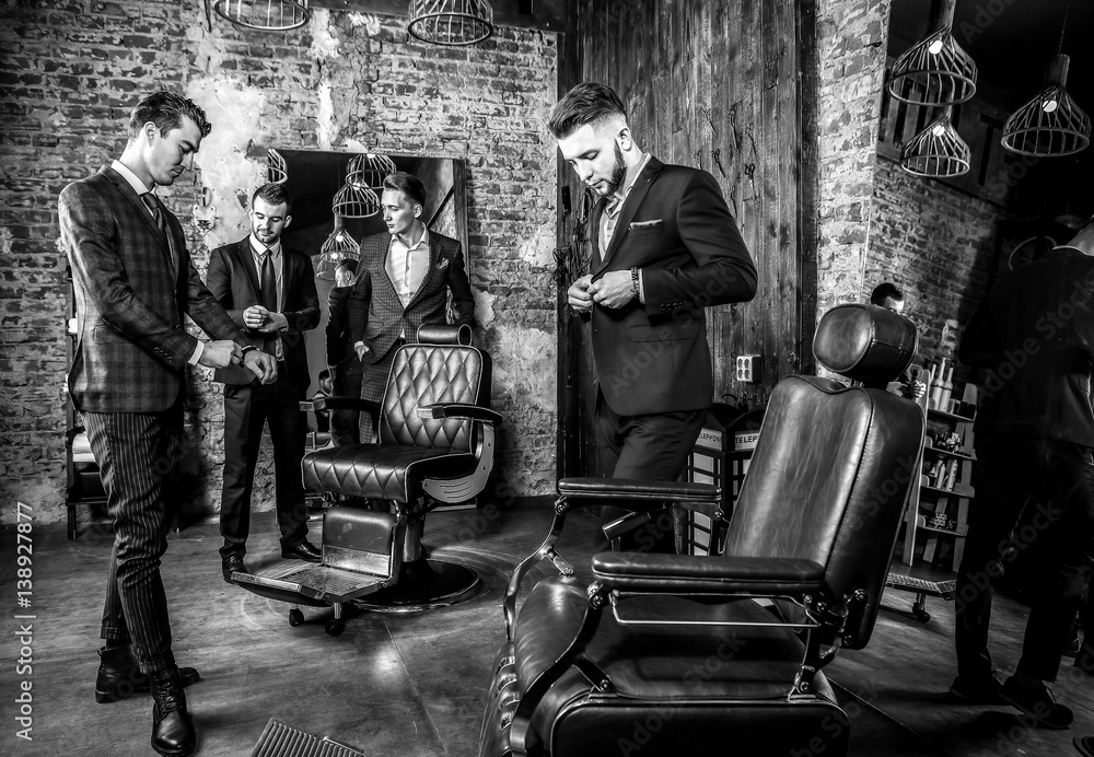 Obraz premium Group of young elegant positive mens pose in interior of barbershop. Black-white photo.
