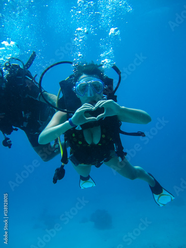 Underwater shoot of a young female diving and showing love signal