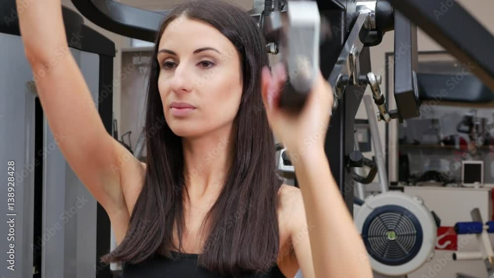 Woman at the gym doing arms exercises on a machine Woman at the gym doing arms exercises on a machine