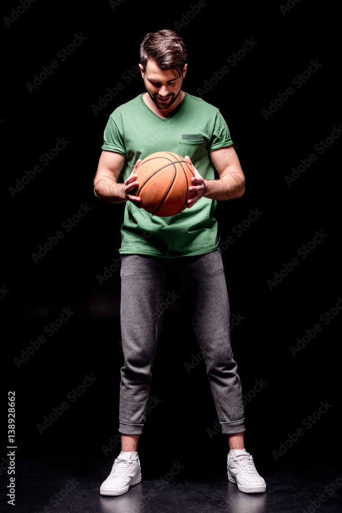 smiling man holding basketball ball and looking down on black smiling man holding basketball ball and looking down on black