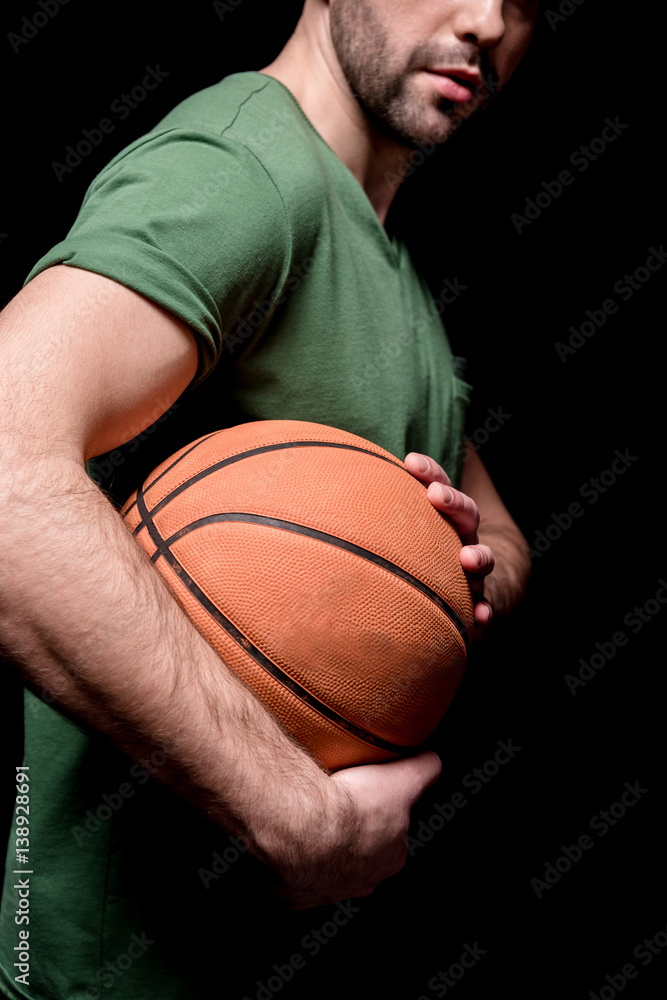 partial side view of man holding basketball ball in hands on black partial side view of man holding basketball ball in hands on black