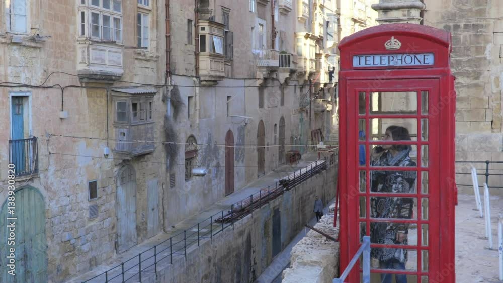 woman in red telephone box in a small village woman in red telephone box in a small village