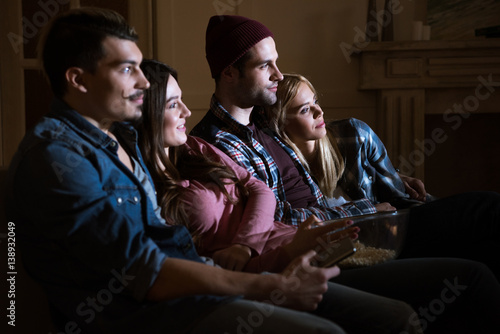 side view of friends watching movie with popcorn at home