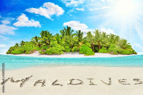 Whole tropical island within atoll in tropical Ocean and inscription  Maldives  in the sand on a tropical island   Maldives.