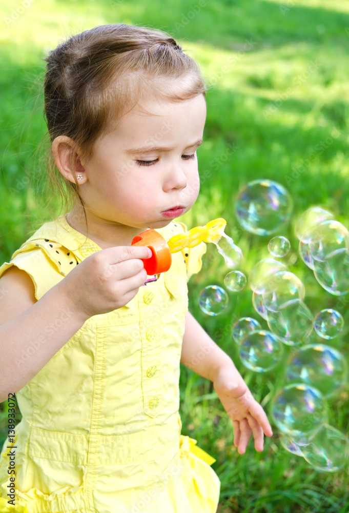 Cute little girl blowing soap bubbles