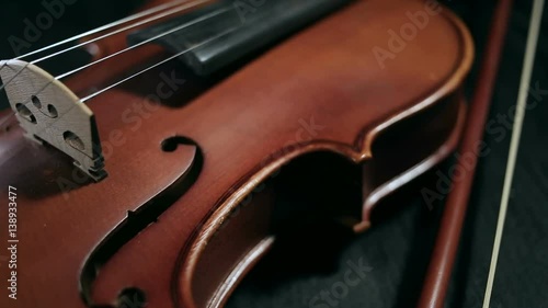 close up dolly shot of part of aged violin on black background
