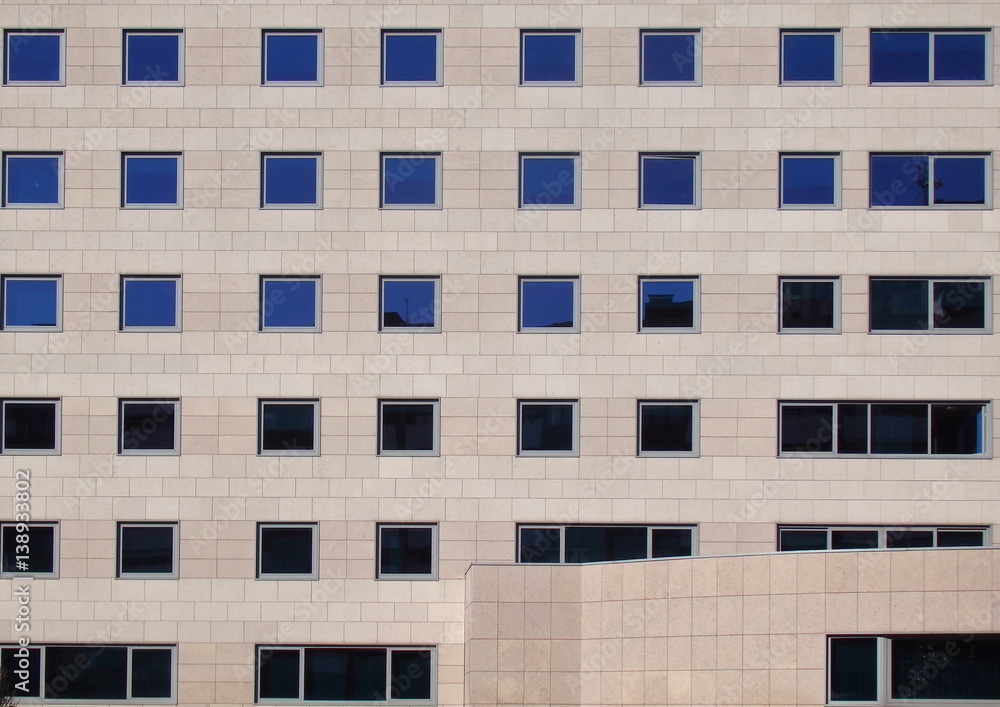 Gray stone facade of a modern building with reflective windows Gray stone facade of a modern building with reflective windows