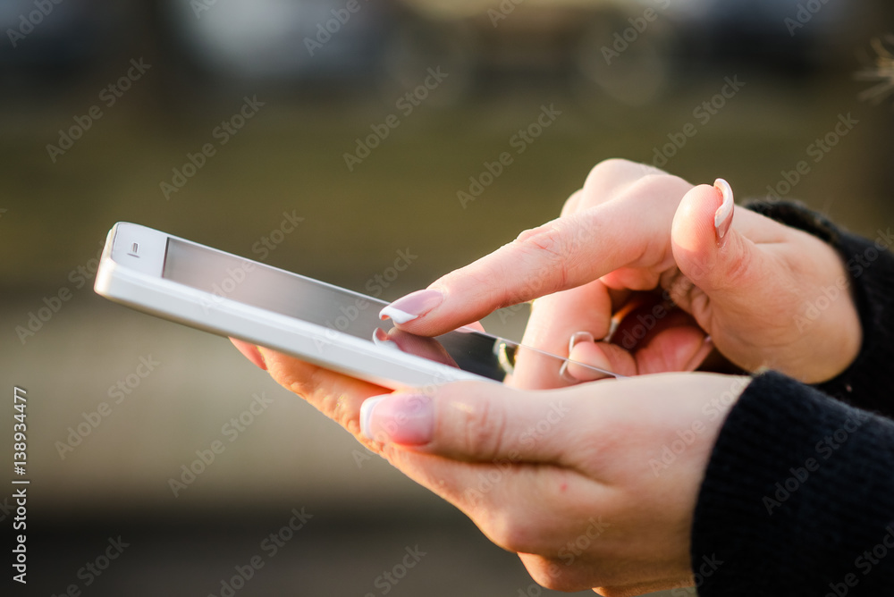 Female Hand Writing a Message on Smart Phone on the Street