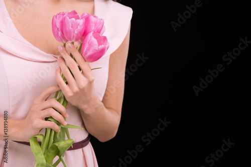 Close-up partial view of woman in dress holding pink tulips on black  international womens day concept