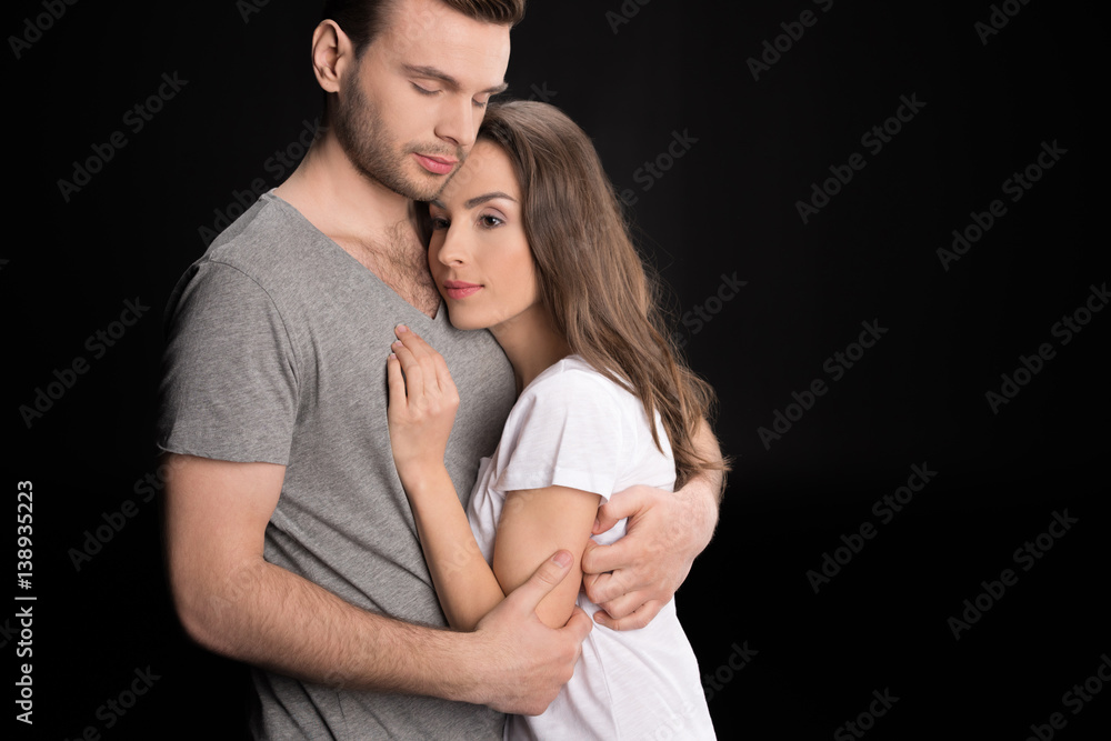Fototapeta premium portrait of pensive woman bonding to man and looking away on black