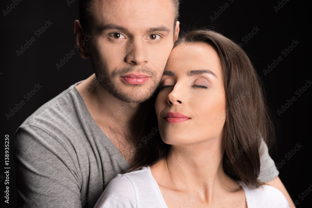 portrait of man looking to camera while hugging woman on black portrait of man looking to camera while hugging woman on black