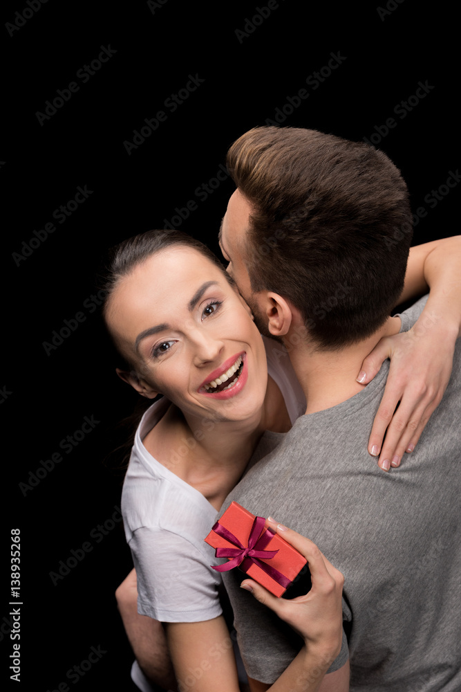 portrait of man hugging happy woman with gift on black, international womens day concept portrait of man hugging happy woman with gift on black, international womens day concept