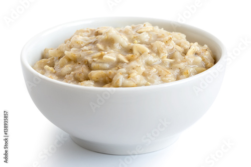Cooked whole porridge oats in white ceramic bowl isolated on white. photo