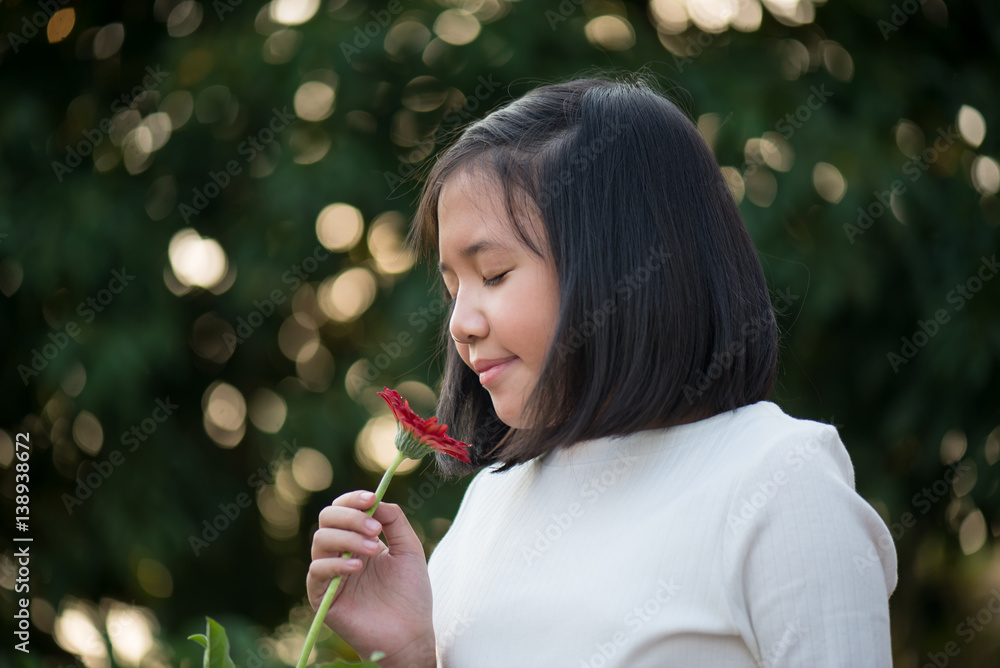 Asian girl is smelling the daisy flower outdoors Asian girl is smelling the daisy flower outdoors